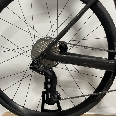 Roda traseira de bicicleta com aro preto, grupo de mudanças metálico e cadeia prateada