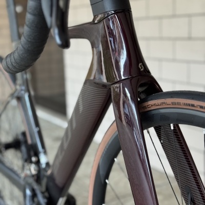 Bicicleta de estrada castanha escura com pneus SCHWALBE e fundo de parede de tijolos clara