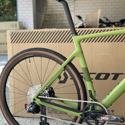 Parte traseira de bicicleta verde com caixa de papelão SCOTT ao fundo