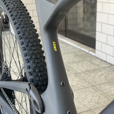 Quadro de bicicleta cinza fosco com texto amarelo COMP e pneu largo com cravos pretos