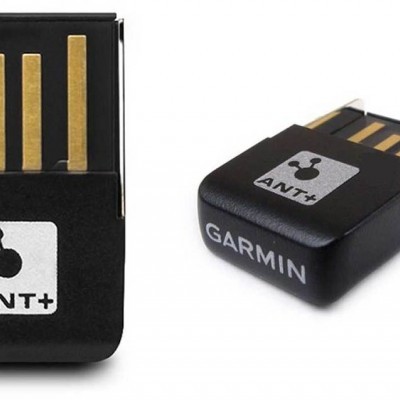Adaptador USB preto com conectores dourados e etiquetas com texto ANT+ e GARMIN