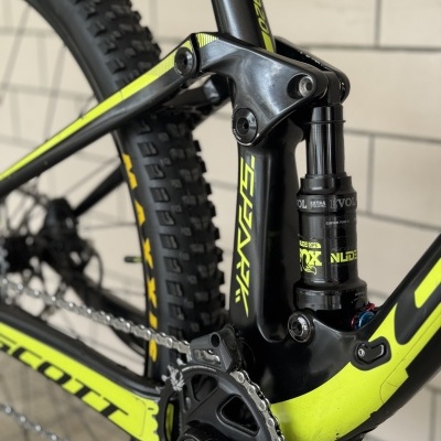Detalhe da suspensão traseira, quadro e corrente de bicicleta preta e amarelo fluorescente