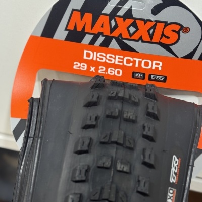 Pneu de bicicleta Maxxis Dissector com embalagem cinza, laranja e preto e texto branco