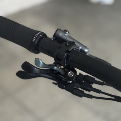 Punho e mudanças de bicicleta pretos com texto SYNTROS e manete cinzenta