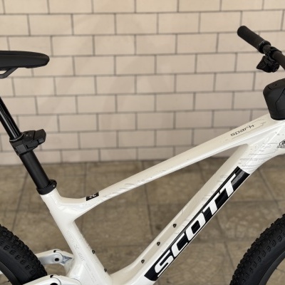 Bicicleta de montanha branca da marca SCOTT encostada numa parede de azulejos brancos