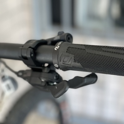 Punho de guidão de bicicleta preto com alavanca de mudança e anel com texto e símbolos.