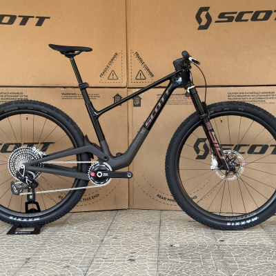 Bicicleta de montanha Scott preta com detalhes rosa, pneus Maxxis e suspensão Rock Shox
