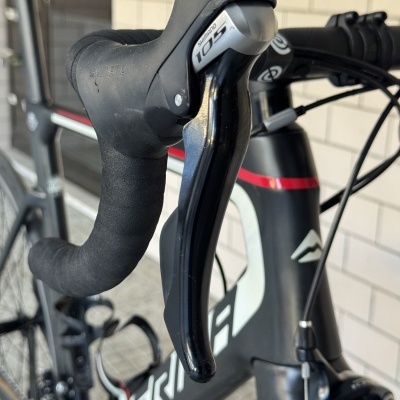 Punho de bicicleta de estrada com manete Shimano 105 e quadro preto com detalhes em branco e vermelho
