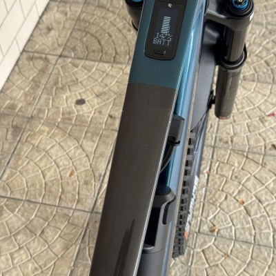 Bicicleta elétrica azul com ecrã digital no guiador e chão de pedras mosaico