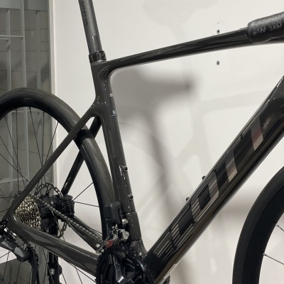 Bicicleta de estrada preta de carbono com nome BOLT no quadro e roda traseira aerodinâmica