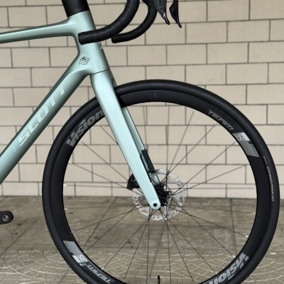 Bicicleta de estrada azul claro SCOTT com rodas Vision Team 35 e guiador preto.
