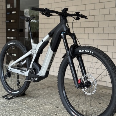 Bicicleta elétrica de montanha Scott preta e cinza com pneus Maxxis e suspensão dianteira