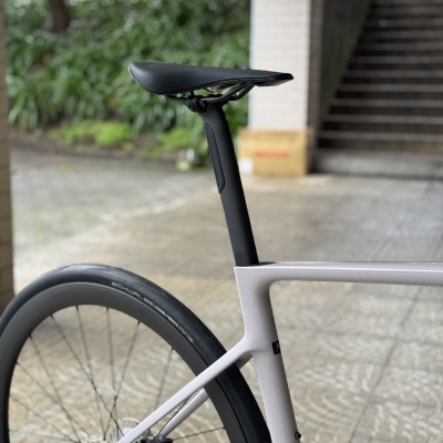 Bicicleta de estrada cinza claro com selim preto e roda traseira em piso pavimentado ao ar livre