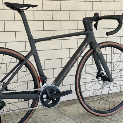 Bicicleta de estrada carbono preto mate com pneus castanho claro e fundo de tijoleira creme