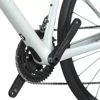 Detalhe de quadro e pedaleira de bicicleta branca com corrente e pneu preto