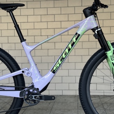 Bicicleta de montanha Scott lilás com suspensão verde e pneus Maxxis