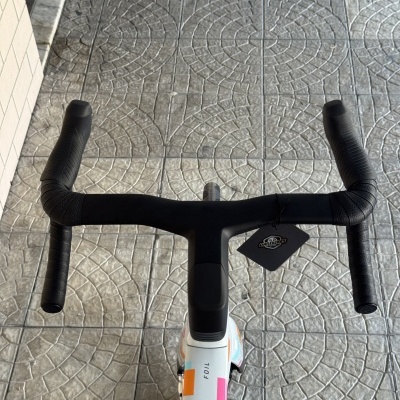 Guidão de bicicleta preto com quadro branco colorido e etiqueta DANIBIKES no chão de ladrilhos cinzentos
