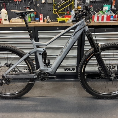 Bicicleta de montanha elétrica cinzenta com pneus Maxxis em oficina