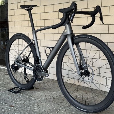 bicicleta de estrada cinzenta mate com guiador drop e pneus Schwalbe ONE em suporte