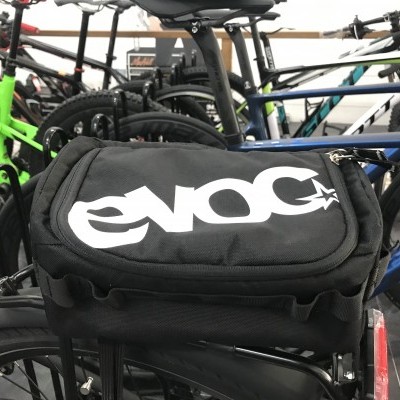 Mala preta EVOC afixada em bicicleta azul na loja