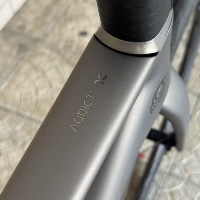 Quadro cinzento de bicicleta com texto ADDICT RC próximo ao guiador, pavimento padrão ao fundo
