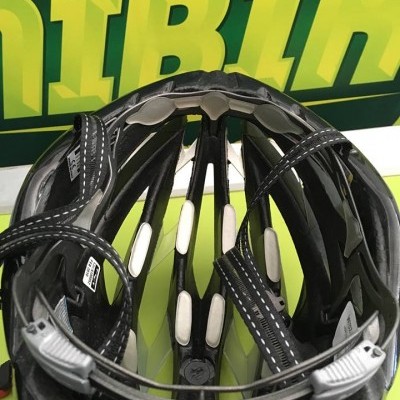 Interior acolchoado de capacete de ciclismo preto com tiras ajustáveis e fundo verde com letras amarelas