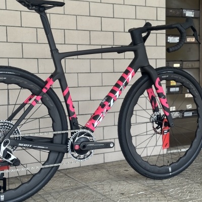 Bicicleta de estrada Scott preta e rosa encostada numa parede