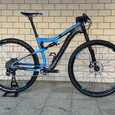 Bicicleta de montanha Cannondale azul e cinza encostada a parede
