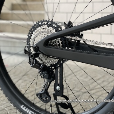 Roda traseira de bicicleta com cassete e corrente, suporte de bicicleta, fundo de escadas e parede branca