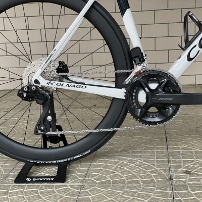 Quadro de bicicleta de estrada branco e preto com roda traseira de carbono e pedaleira próxima