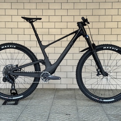 Bicicleta de montanha preta com pneus Maxxis e quadro de carbono