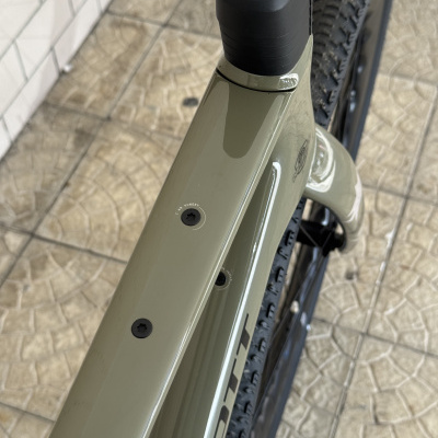 Quadro de bicicleta verde mate com rodas pretas e azulejo bege no chão