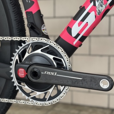 Roda dentada e braço de pedaleira de bicicleta em carbono preto com texto Red e quadro rosa com padrões