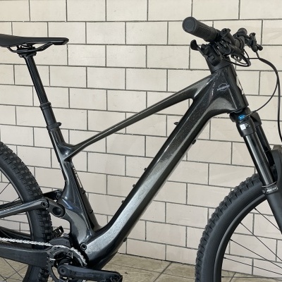 Bicicleta de montanha elétrica preta encostada numa parede de azulejos brancos