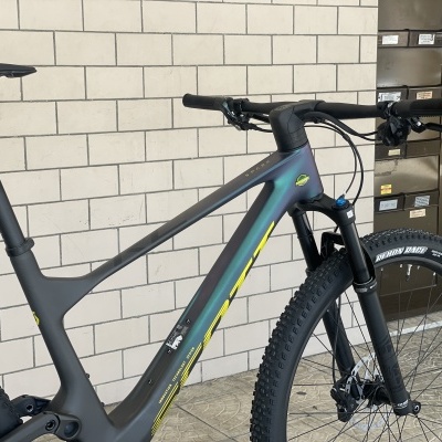 Bicicleta de montanha cinzenta com detalhes em amarelo junto a uma parede de tijolos claros