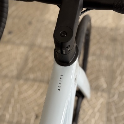 Bicicleta branca com guiador preto e texto ADDICT no quadro