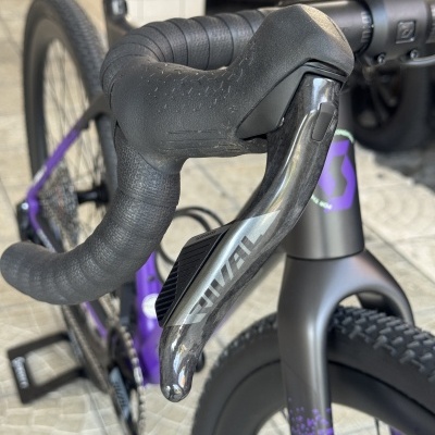Guiador preto texturizado e desviador RIVAL em bicicleta cinza com detalhes roxos