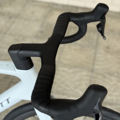 Guidão de bicicleta de estrada preto com manípulos integrados montado em bicicleta branca