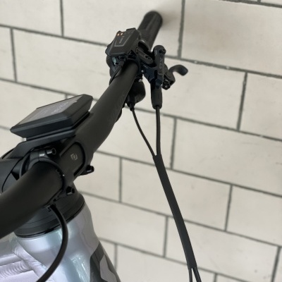 Guiador de bicicleta com mostrador digital e alavanca de travão sobre fundo de azulejos brancos