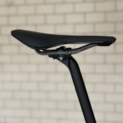 Selim de bicicleta preto montado em estrutura preta contra parede branca