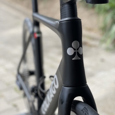 Bicicleta de estrada preta com logotipo de trevo branco no tubo da frente