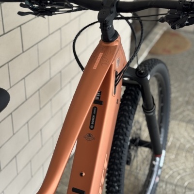 Bicicleta elétrica de montanha laranja com pneus pretos e guiador preto