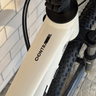 Detalhe do quadro branco de bicicleta com texto CONTRA e pneus pretos de piso robusto