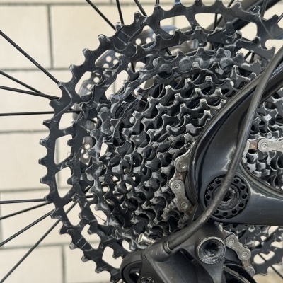 Cassete de bicicleta preta com várias engrenagens e componente mecânico numa parede de azulejos brancos