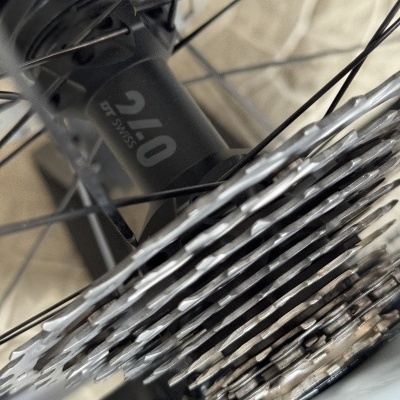 Detalhe do cubo traseiro DT SWISS 240 numa roda de bicicleta com cassete prateada e raios pretos