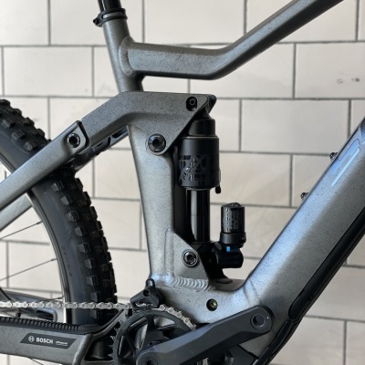 Parte do quadro de uma bicicleta de montanha elétrica cinzenta com suspensão traseira e componentes Bosch