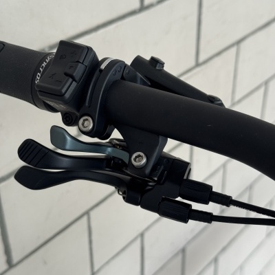 Punho de bicicleta preto com comandos e texto SYNCROS em fundo de azulejos brancos