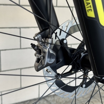 Roda de bicicleta com disco de travão e pinça Shimano prateadas e suspensão preta com etiqueta amarela