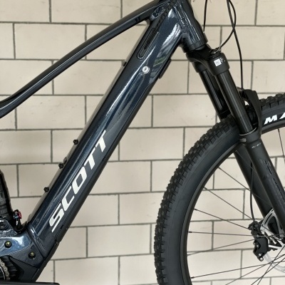 Bicicleta elétrica SCOTT preta junto a parede branca de azulejos