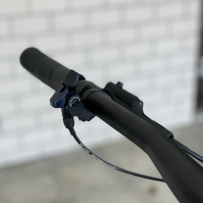 Guiador preto de bicicleta com seletor rotativo LOCK UNLOCK e fundo de parede de tijolos brancos